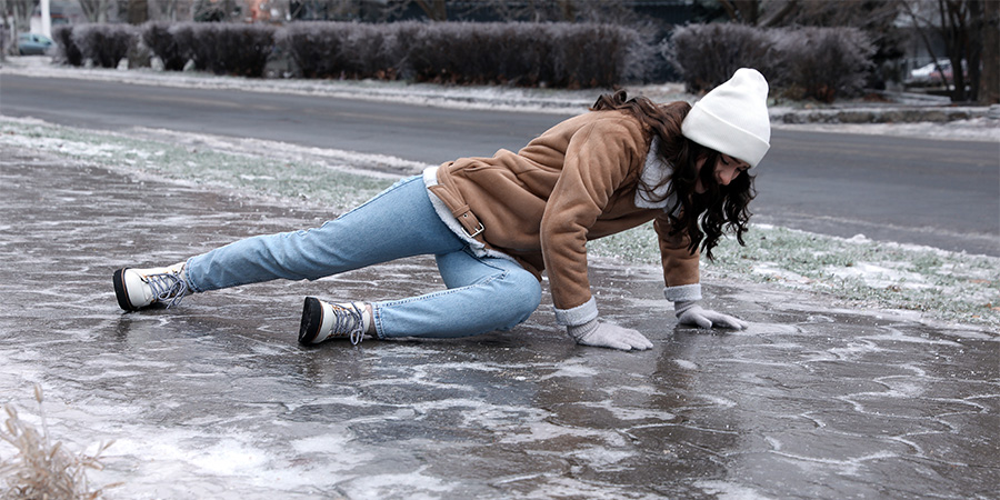 White woman with a white winter hat slips on the ice