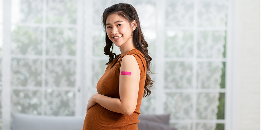 Asian pregnant woman with bandage on her arm from vaccination